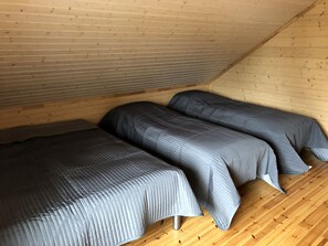 A small, cozy room with two beds, wooden walls, and a sloped ceiling. - Comfortable cottage on a beautiful lake (Uro)