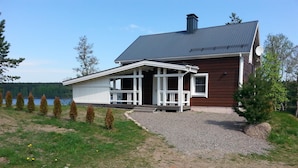 A two-story house with a porch, a chimney, and a view of a lake. - Comfortable cottage on a beautiful lake (Uro)
