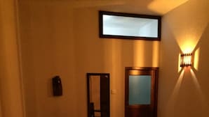 A hotel room with a bed, a chair, a desk, and a door. - Paddy House Villa (Ranna)