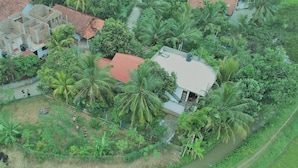 An aerial view of a residential area with houses, palm trees, and a narrow water channel. - Paddy House Villa (Ranna)
