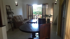 A living room with a sofa, a dining table with chairs, a staircase, and a potted plant. - Paddy House Villa (Ranna)