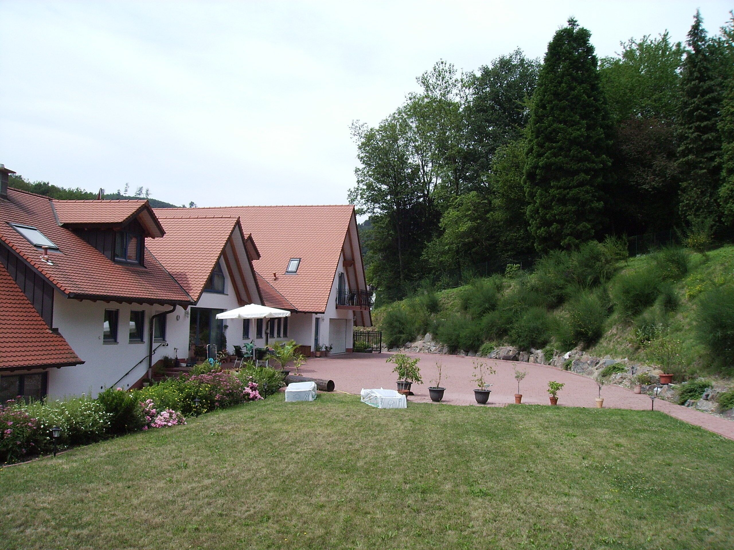 A traditional chalet with a sloped roof, a patio area with outdoor seating, and a well-maintained garden.