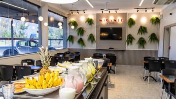 A buffet area with a variety of food items and beverages, including bananas, pineapple, and milkshakes.