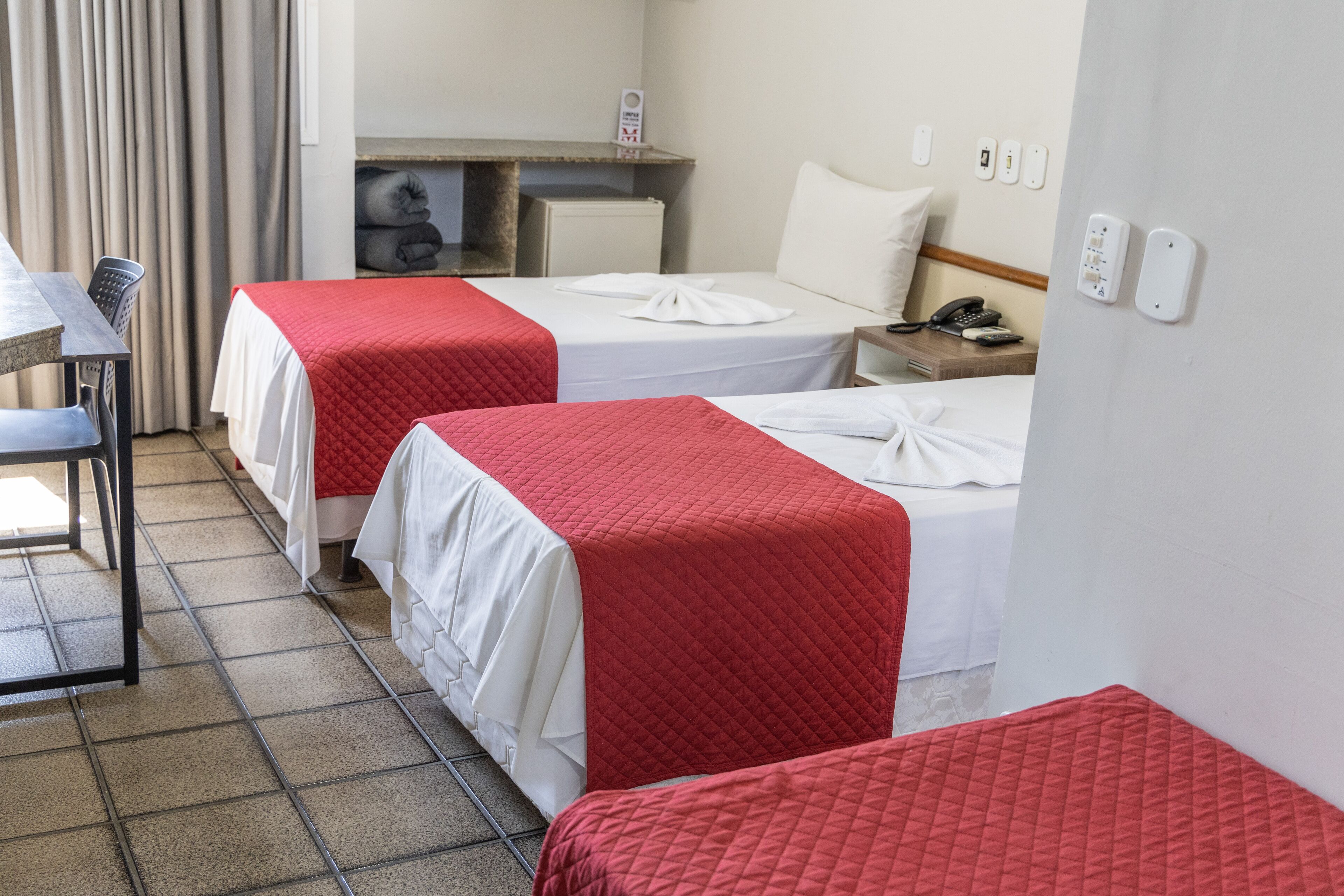 A hotel room with two beds, a desk, and a chair.