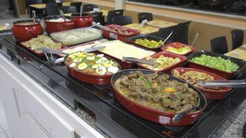 Un bufé con diversos platos, incluyendo carnes, verduras y postres.
