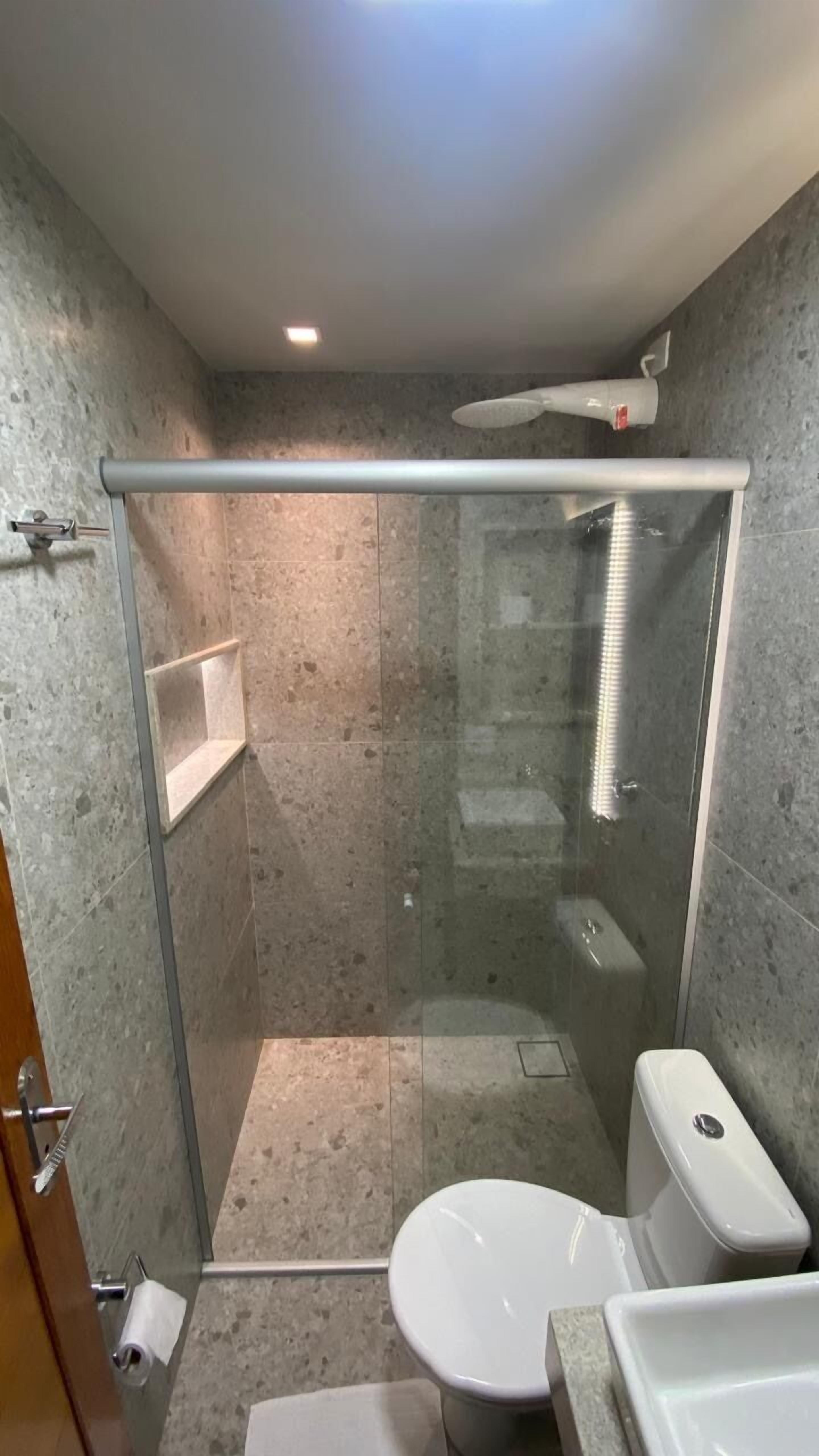 Un baño con ducha de vidrio, inodoro y lavamanos.