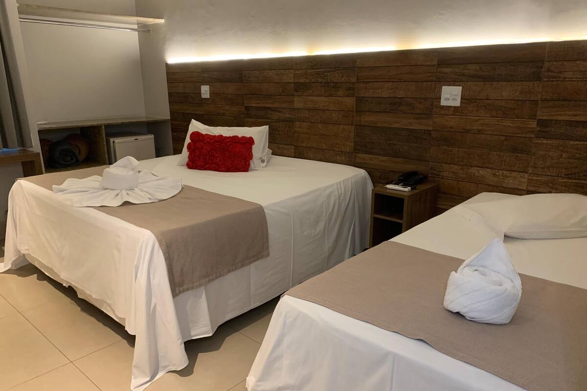 A hotel room with two beds, a wooden headboard, a bedside table with a phone, and a towel on each bed.