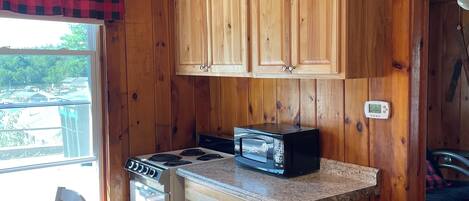 A compact kitchen with wooden cabinets, a stove, and a microwave.