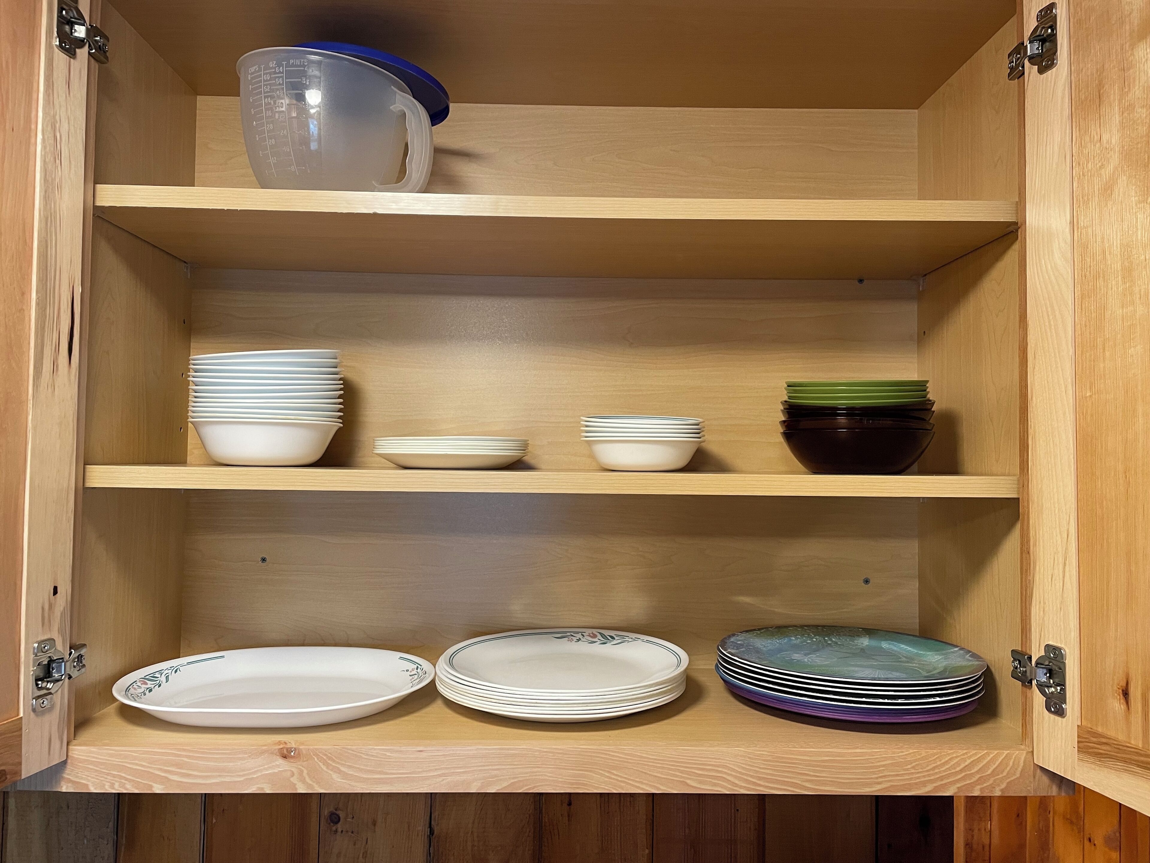 A wooden cabinet with multiple shelves holding various dishes and bowls.