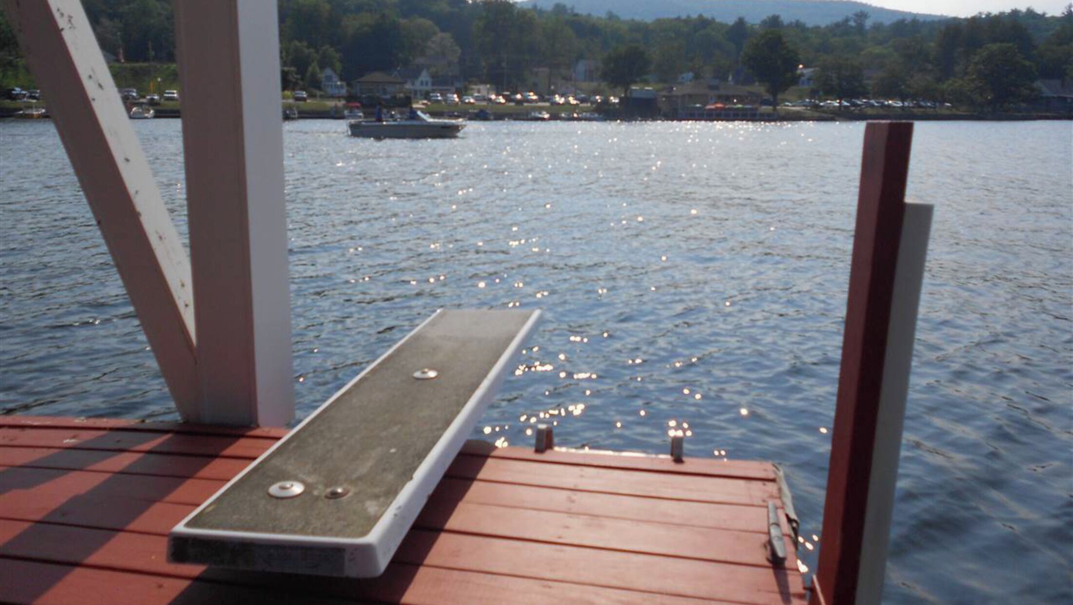 A wooden dock extending over a calm lake with a boat in the distance.