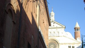A narrow cobblestone street with historic buildings, including a prominent church with a large circular window and a bell tower. - VIOLINS AND MUSIC APARTMENT IN DOWNTOWN CREMONA - AT ANTONELLA'S HOUSE - (Cremona)