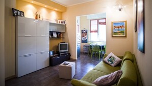 A compact living space with a kitchenette, a green sofa, and a dining area. - VIOLINS AND MUSIC APARTMENT IN DOWNTOWN CREMONA - AT ANTONELLA'S HOUSE - (Cremona)
