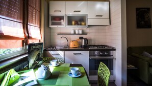 A compact kitchen with white cabinets, a gas stove, and a window with blinds. - VIOLINS AND MUSIC APARTMENT IN DOWNTOWN CREMONA - AT ANTONELLA'S HOUSE - (Cremona)