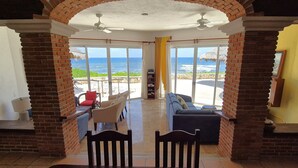 Une chambre avec vue sur l’océan, un ventilateur de plafond et un canapé.