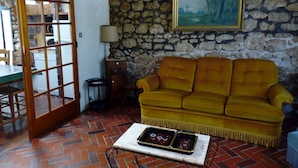 A living room with a stone wall, a yellow sofa, a table with a tray, and a lamp.