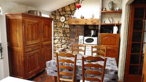A kitchen with wooden cabinets, a stone wall, and a table covered with a milk-themed tablecloth.