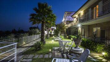 A well-lit outdoor patio area with a seating arrangement, a palm tree, and a building with balconies.