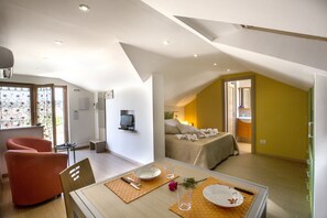 Moderni hotellihuone, jossa on ruokailutila, keltainen tehosteseinä ja televisio.