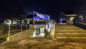 Un edificio moderno con una entrada destacada, una escalera que conduce a la entrada principal y un camino bien iluminado.