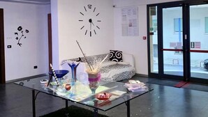 Un área de recepción con una mesa de vidrio, un reloj y un sofá.