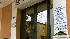 Entrada de un hotel con un letrero que dice "HD DOMUS" y un aviso sobre servicios que incluyen WiFi, internet y control de clima.