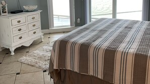 Une chambre dotée d’un grand lit, d’un ventilateur de plafond, d’une commode, d’un téléviseur et offrant une vue sur un paysage enneigé grâce à une porte-fenêtre coulissante.