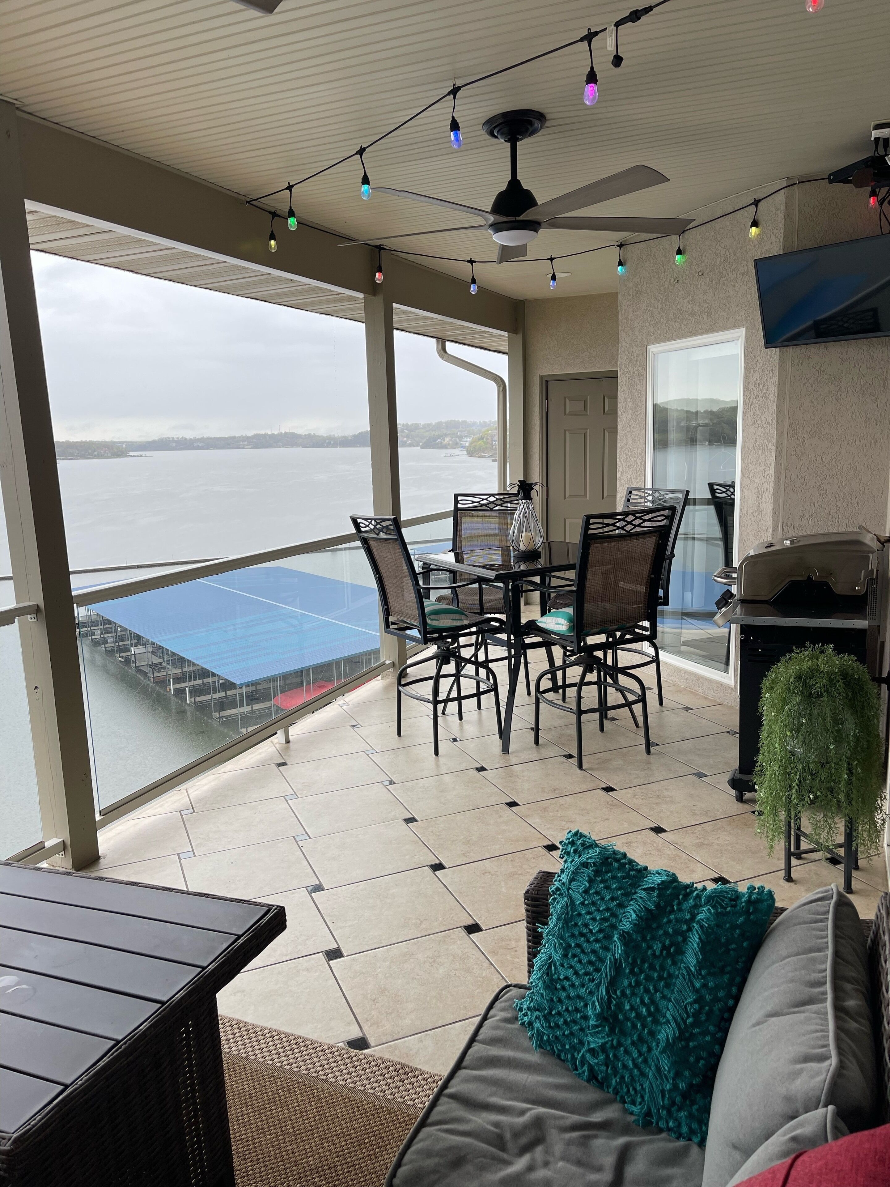 Ein Balkon mit Tisch und Stühlen, einem Deckenventilator und Blick auf ein Gewässer.