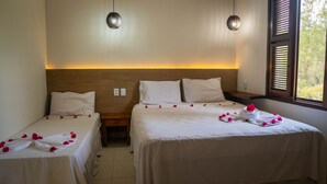 Een hotelkamer met twee bedden, een houten hoofdbord, nachtkastjes en een raam met zonwering.