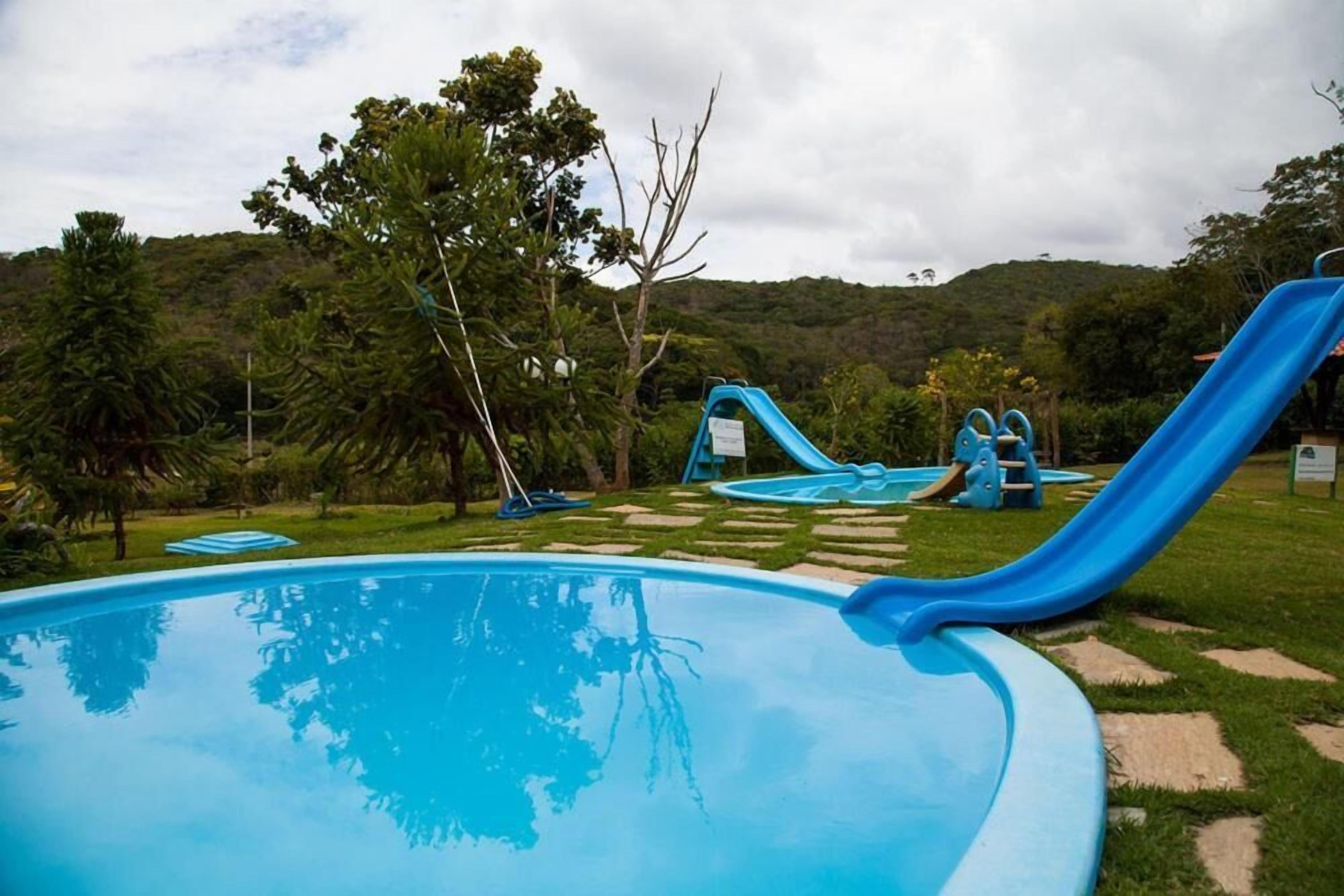 A swimming pool with a blue slide and a small kiddie pool.