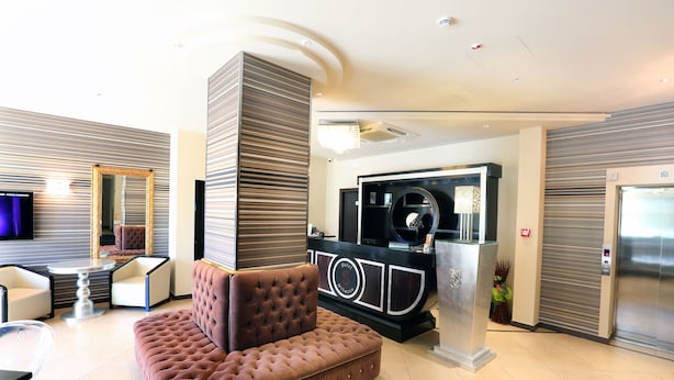 A modern lobby with a tufted brown sofa, a reception desk, and a large mirror.