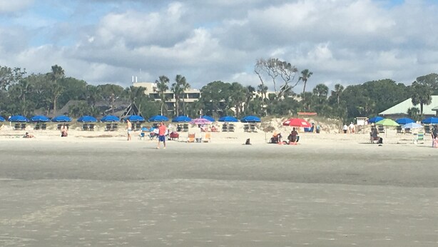 Une plage avec des parasols et des gens.