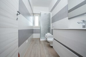 Un baño moderno con ducha, inodoro y lavamanos.