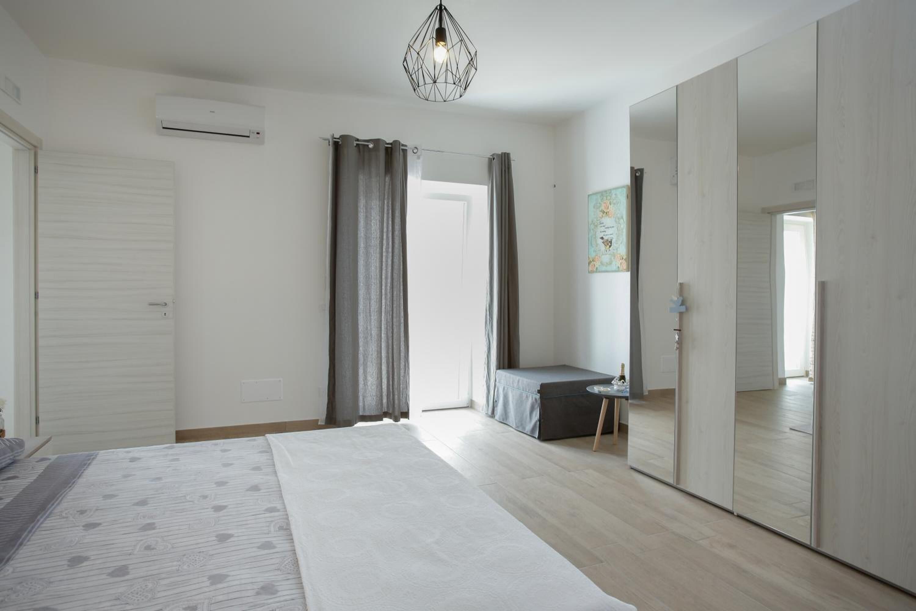 A bedroom with a bed, a bedside table, a mirror, and a wardrobe.