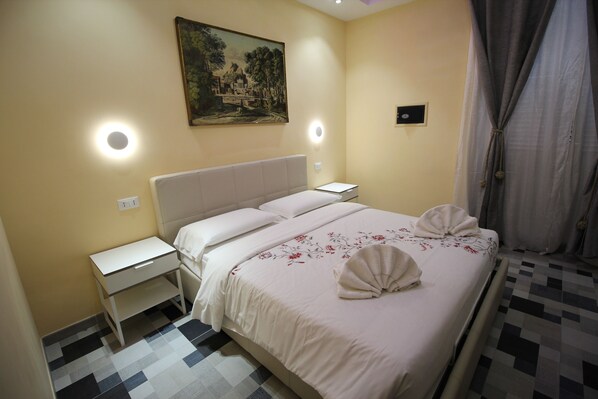 A hotel room with a bed, bedside tables, a painting on the wall, and a check-in station. - Quest House Lihong (Rome)