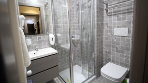 A modern bathroom with a glass-enclosed shower, a white sink, and a toilet.