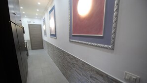 A hallway with a tiled floor, a stone accent wall, and a door at the end.
