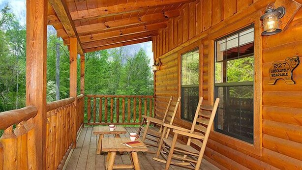 A wooden cabin with a porch, rocking chairs, and a table with cups and books. - Absolutely Bearable: S/Secluded, Honeymoon, Hot Tub, Games, near Attractions! (Sevierville)