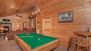 A wooden interior with a pool table, a fireplace, and a framed photograph on the wall. - Absolutely Bearable: S/Secluded, Honeymoon, Hot Tub, Games, near Attractions! (Sevierville)