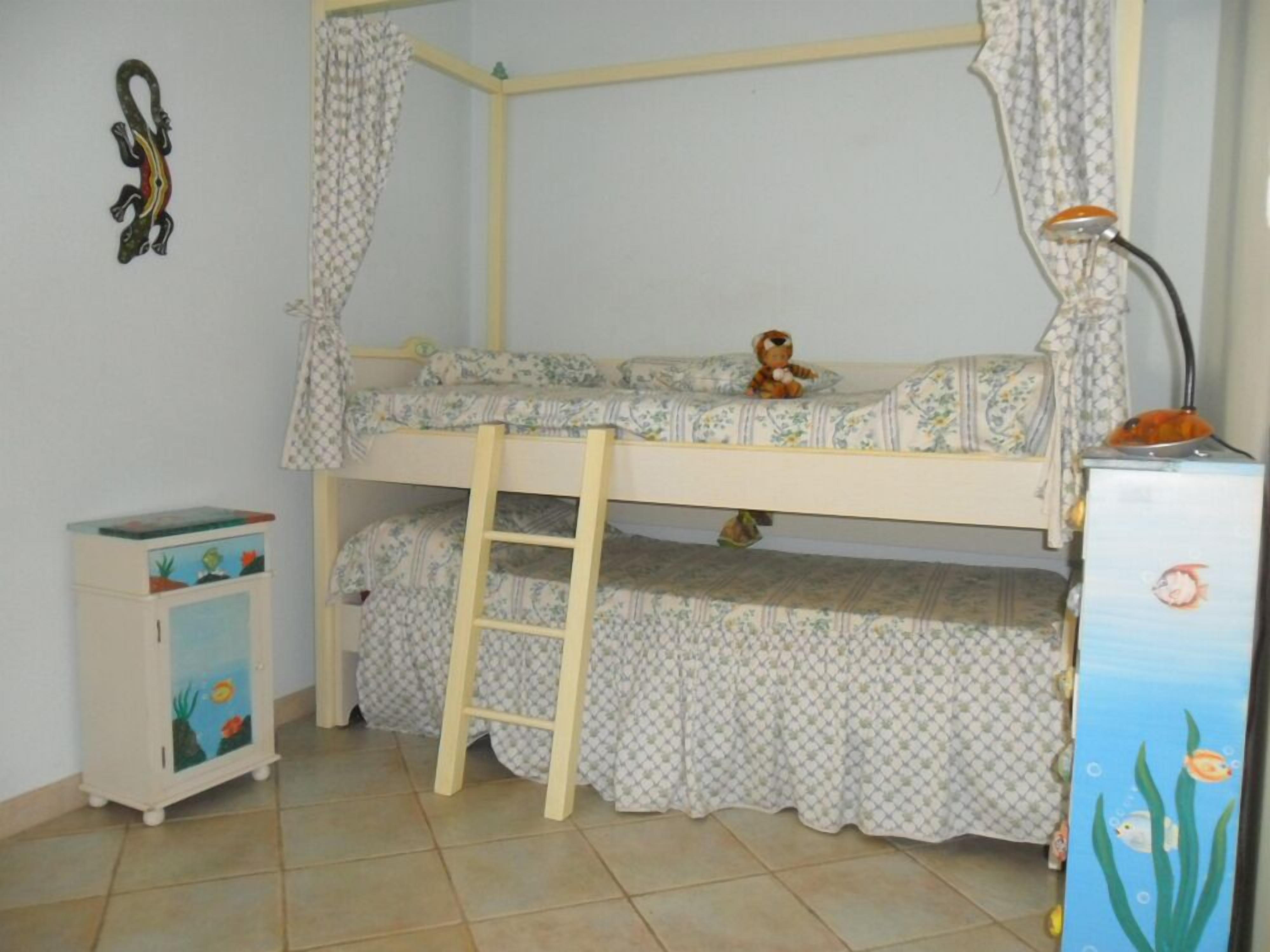 A bunk bed with a ladder, a small cabinet with a fish design, and a toy on the top bunk.