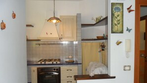 Eine kleine Küche mit Gaskochfeld, Backofen und einer Pendelleuchte.