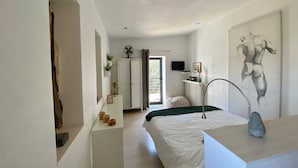 A modern bedroom with a large bed, a desk, a chair, a radiator, a TV, and a window. - Ô Chambre d'hôtes (Le Gua)