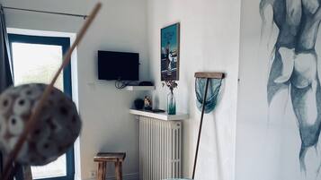 Una habitación moderna con una cama, un televisor en la pared, un cuadro y una ventana con vistas.