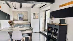 A modern kitchen with a wooden table, chairs, and a coffee machine. - Ô Chambre d'hôtes (Le Gua)