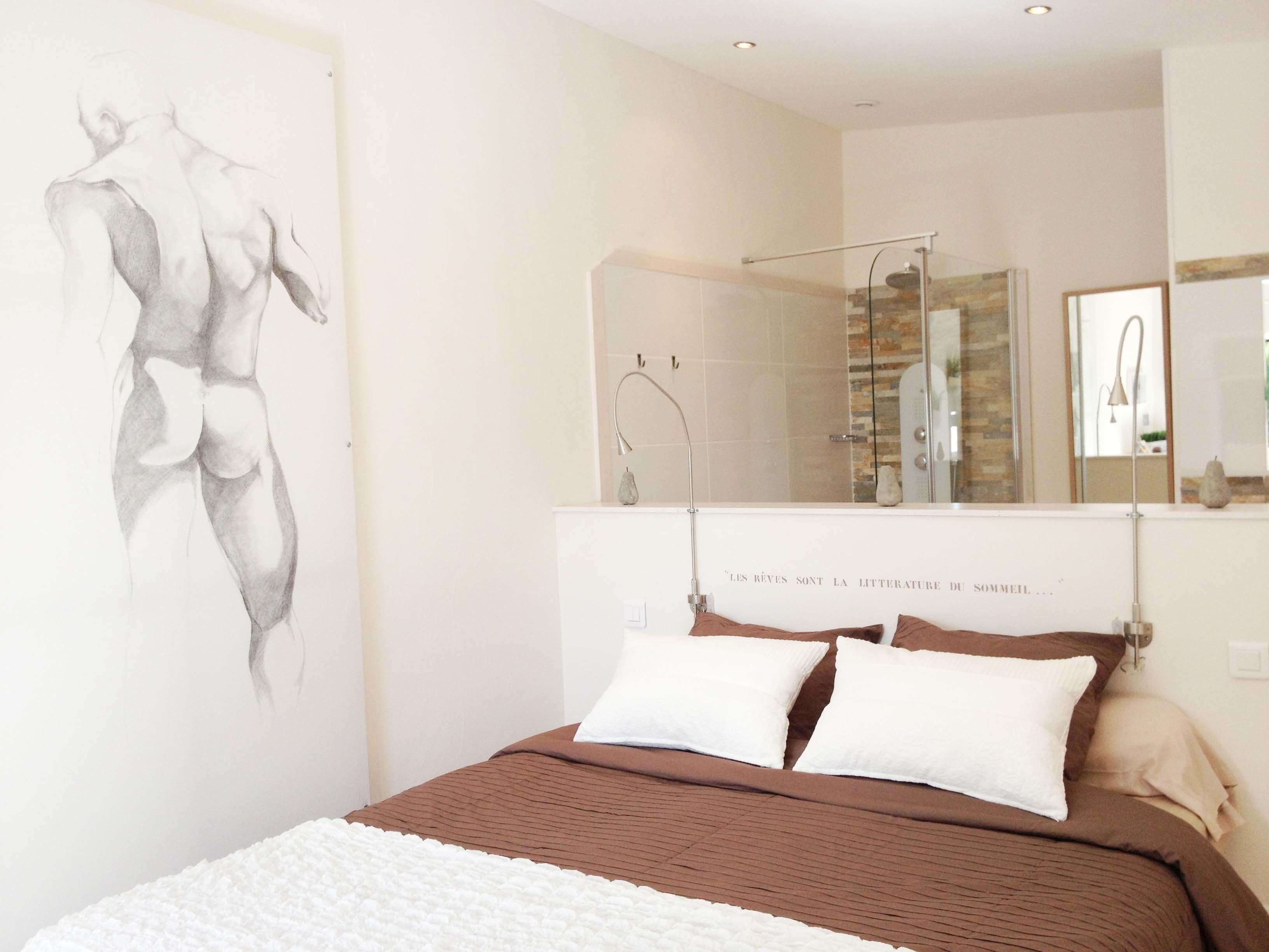 Un dormitorio con una cama grande, ducha y espejo adosado a la pared.