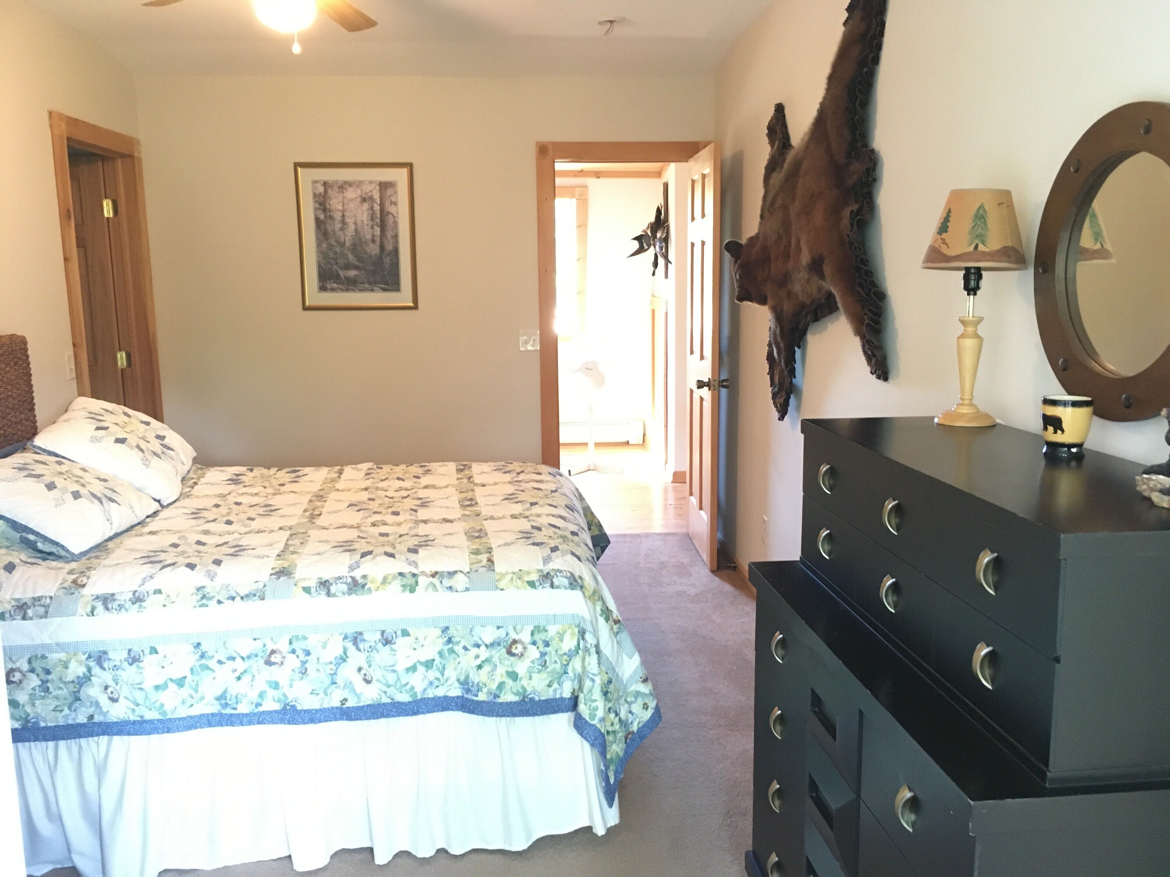 Una camera da letto con un letto, una cassettiera e una testa di animale appesa al muro.