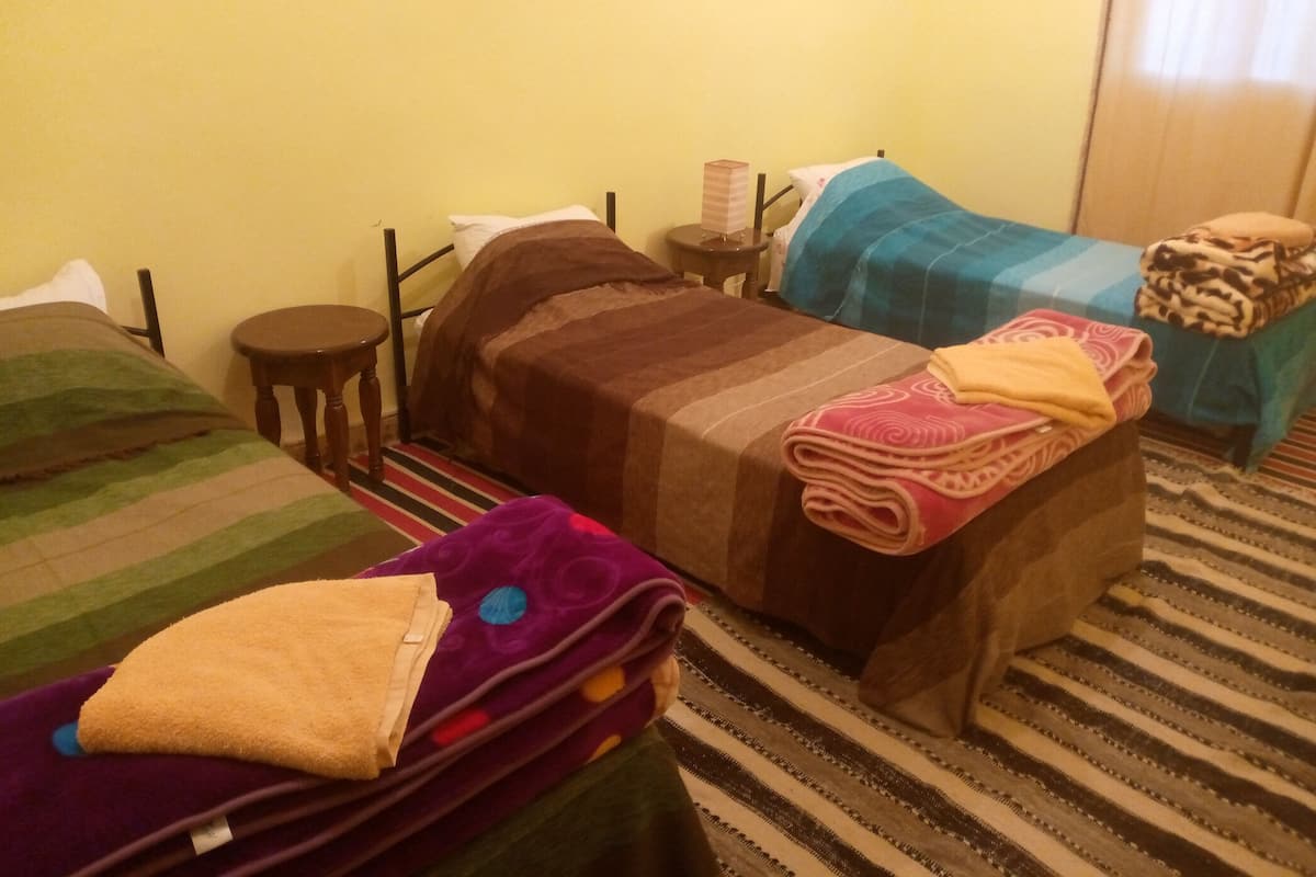 A room with two beds, a small round table, and a striped carpet.
