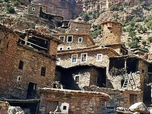 A traditional stone building with multiple levels, a balcony, and a small tower. - Auberge restaurant Les Coquelicots (Ait Tamlil)