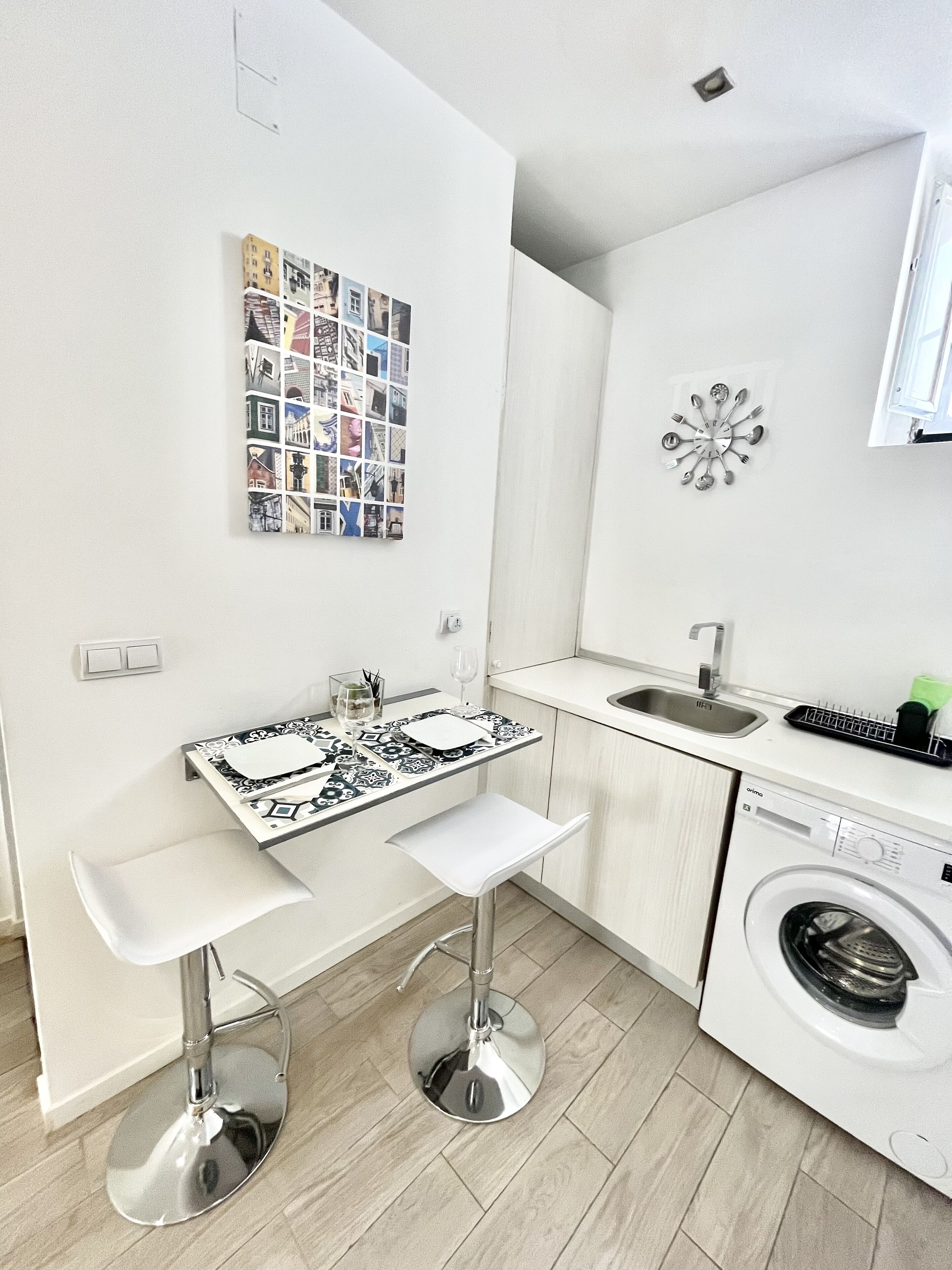 A compact kitchen with a washing machine, a tiled backsplash, and a wall-mounted utensil holder.