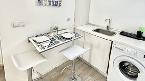 A compact kitchen with a washing machine, a tiled backsplash, and a wall-mounted utensil holder. - NEW HOUSE DESIGN, TYPICALISBON (Lisboa)
