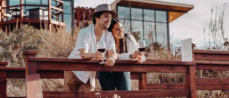 A couple sitting on a wooden bench with a modern building in the background.
